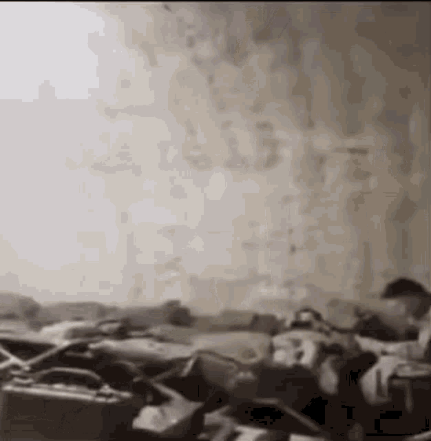 a black and white photo of a person laying on a bed with a suitcase on the floor .
