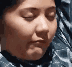 a woman in a plaid shirt is making a funny face with her eyes closed .