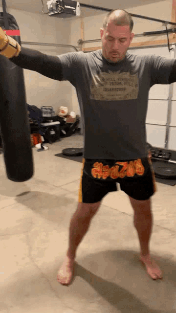 a man wearing a t-shirt that says ' valley view ' on it stands in front of a punching bag