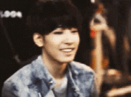 a young man in a denim jacket is smiling and looking at the camera .