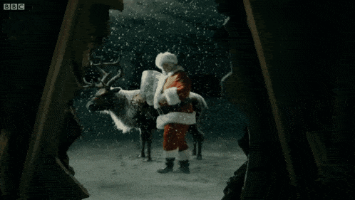 a man dressed as santa claus stands next to a bbc logo