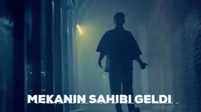 a silhouette of a man walking down a dark hallway with the words " mekanin sahibi geldi " written on the bottom