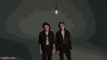 a group of three women are standing next to each other in front of a light bulb .