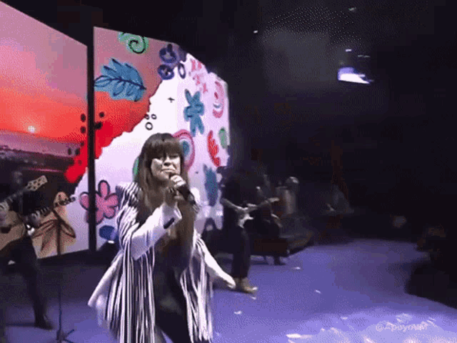 a woman singing into a microphone on stage