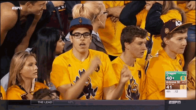 a group of people sitting in a stadium watching a game between oregon and arizona