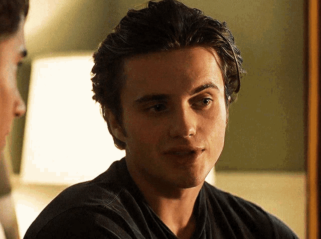 a man in a black shirt is looking at another man in a mirror