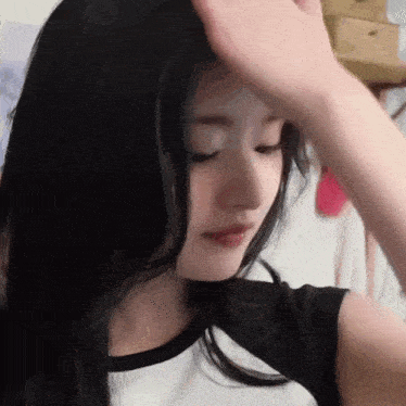 a woman with long black hair is touching her forehead