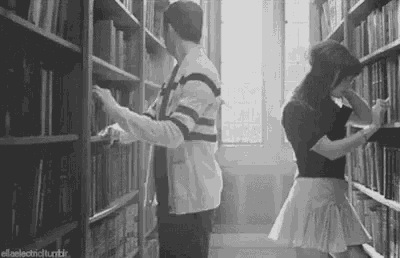 a man and a woman are kissing in a library .