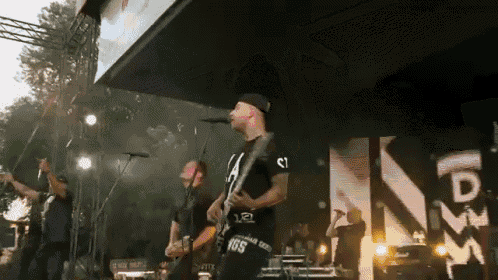 a man singing into a microphone while playing a guitar with the number 165 on his shirt