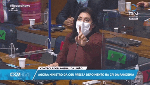 a woman wearing a mask is talking into a microphone on a television screen