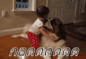 a baby is playing with a dog on the floor and the dog is licking the baby 's face .