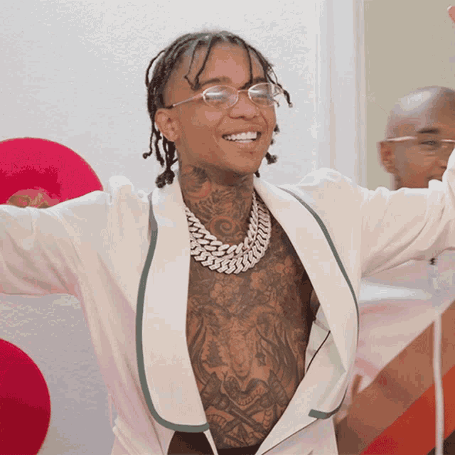 a man with tattoos on his chest is wearing glasses