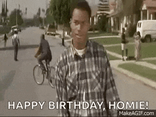 a man in a plaid shirt is walking down a street and says `` happy birthday , homie ! ''