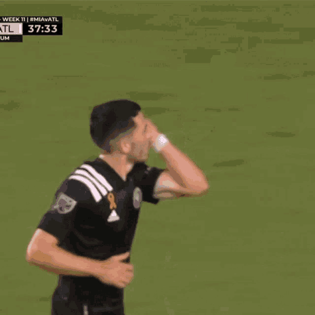 a soccer player in a black adidas jersey celebrates