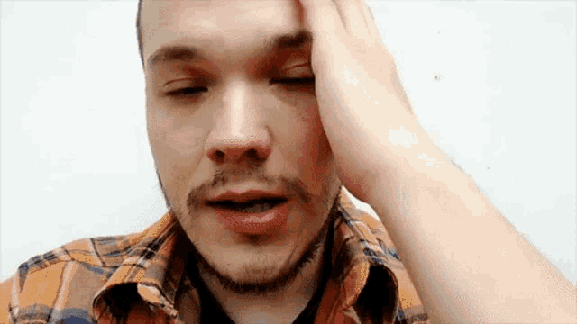 a man with a beard is holding his head in pain