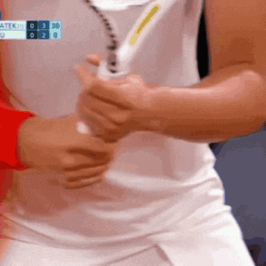 a person holding a tennis racquet in front of a scoreboard that says atek
