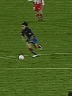 a blurry picture of two soccer players on a field with one wearing a blue jersey