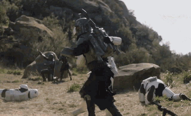a storm trooper is laying on the ground while another storm trooper is running away
