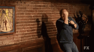 a man is singing into a microphone in front of a brick wall that says fx