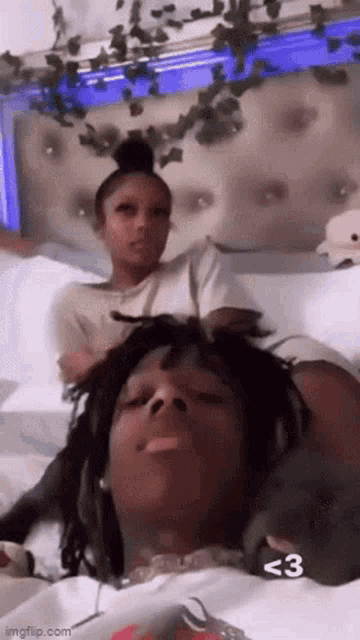 a man and a woman are laying on a bed . the woman is wearing headphones .