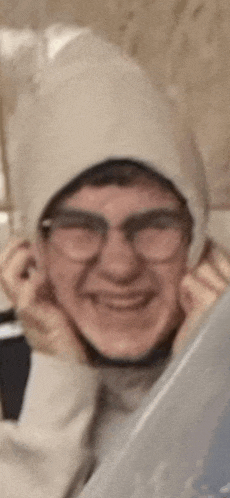 a man wearing a hat and glasses is smiling .