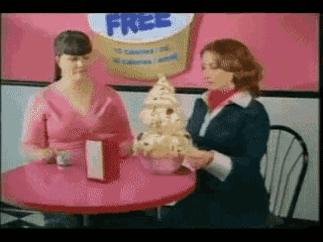 two women sitting at a table with a sign that says free on it