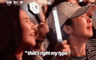 a woman is crying while holding a light stick and saying that 's right my type