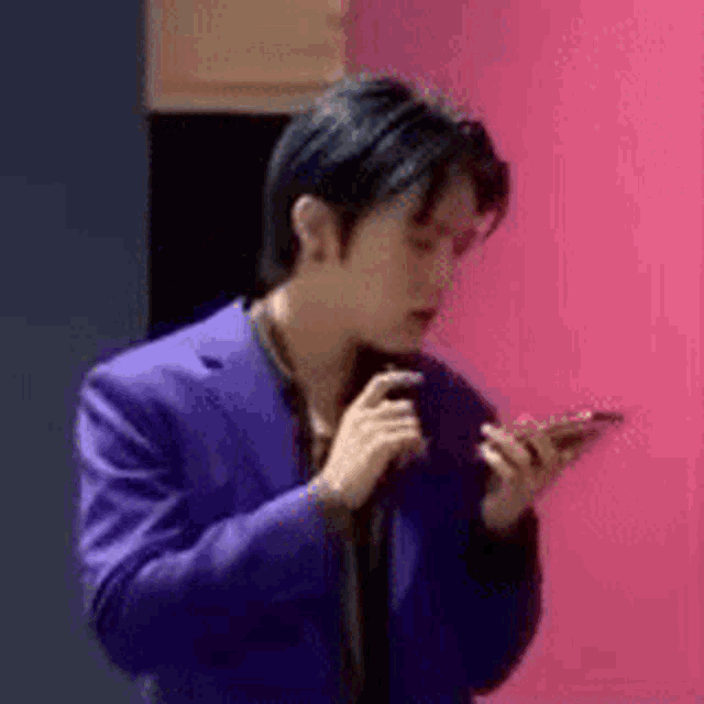 a man in a purple suit is holding a cell phone in his hand .