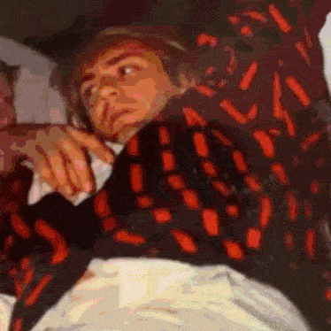 a man in a red and black shirt is laying down