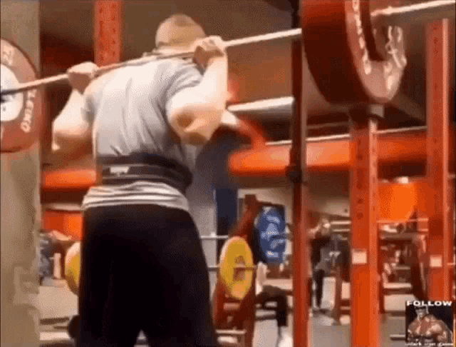 a man is squatting with a barbell in a gym with a sign that says follow