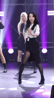 a woman in a white shirt and black skirt is dancing on a stage with other women .