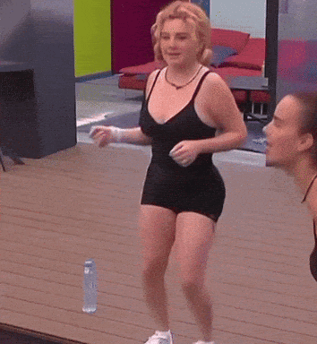 a woman in a black tank top and shorts is dancing on a deck
