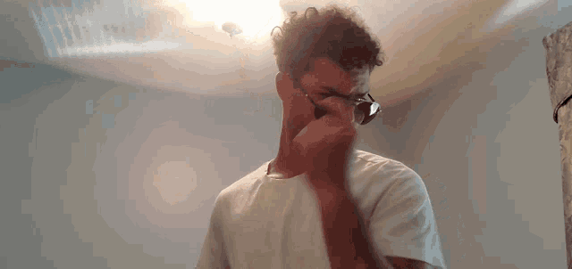 a man wearing sunglasses and a white shirt looks down at something