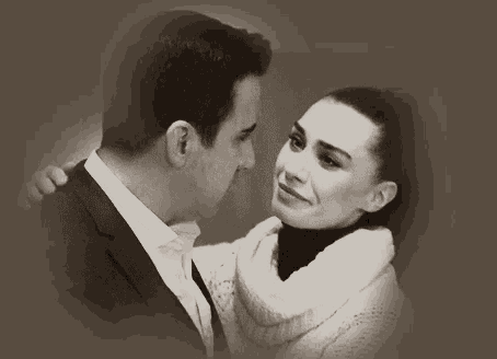 a man and a woman are looking at each other and the woman is touching the man 's face