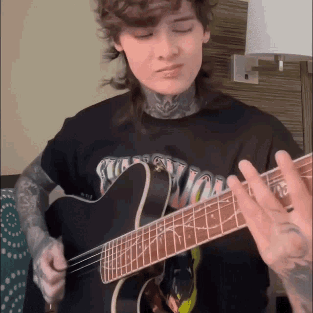 a man playing a guitar with a shirt that says guns n roses