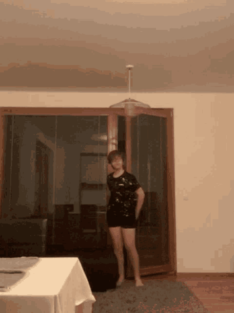 a woman in shorts stands in front of a sliding glass door in a living room