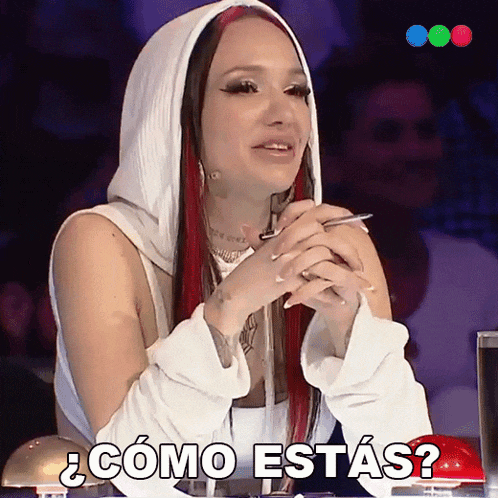a woman with red hair is sitting in front of a red button that says " como estas "