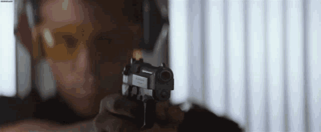 a man is pointing a gun at the camera while wearing safety goggles