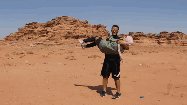 a man is carrying a woman in his arms and the shorts he is wearing say nike
