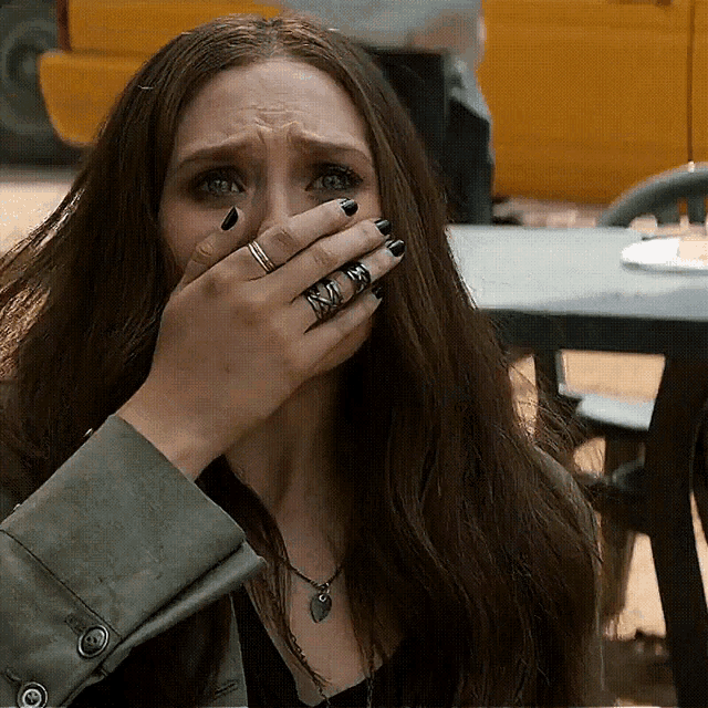 a woman with rings on her fingers is covering her face