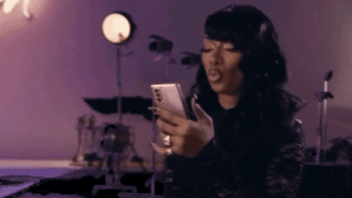 a woman is looking at her phone in a room with purple walls .