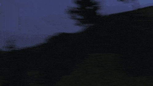 a giant robot is flying over a hill with flames coming out of it 's tail