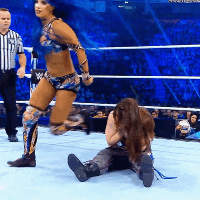 a woman in a wrestling ring with a referee in the background