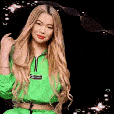 a woman with long blonde hair is wearing a green jacket with the word chanel on it