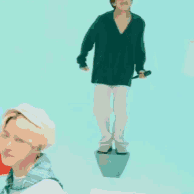 a man is standing on a block in the water while another man stands behind him .