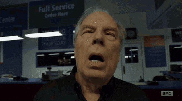 a man is yawning in front of a sign that says full service