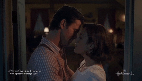 a man and woman kissing in front of a hallmark ad