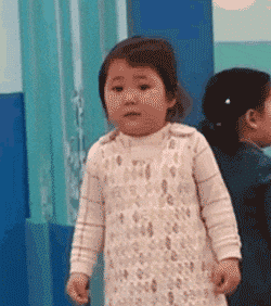 a little girl in a white dress is standing in front of a blue curtain