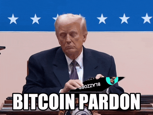 a man in a suit and tie sitting at a desk with a sign that says bitcoin pardon