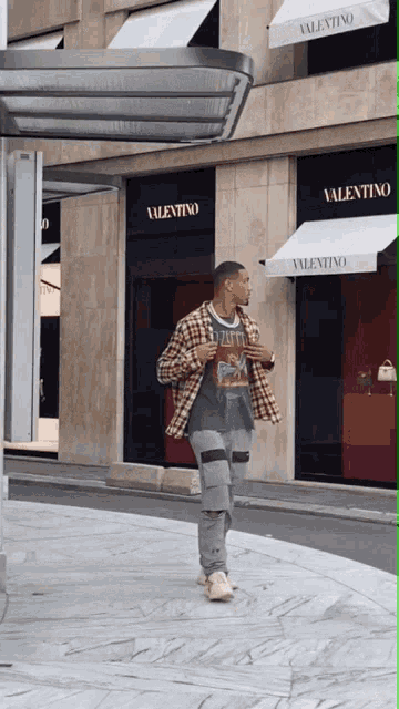a man is walking in front of a store that says valentino